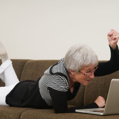 Woman on couch with laptop being excited