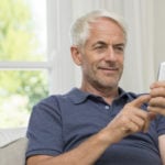 White haired man texting