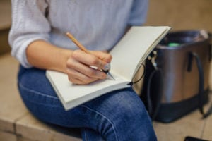 Woman's hand writing something in a notebook.