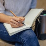 Woman's hand writing something in a notebook.