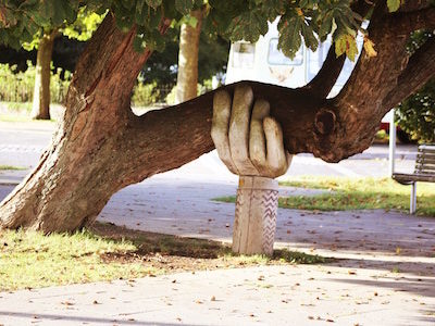 Sculpture of a large hand holding up a large tree limb